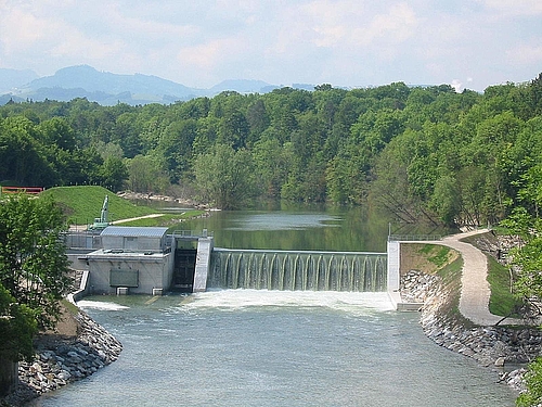 Ansicht des Wasserkraftwerks Dorfmühle mit Stausee und Wald im Hintergrund